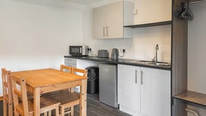 A compact kitchen with a wooden table and chairs, a microwave, a kettle, and a dishwasher. - 1 bedroom accommodation in Battle (Battle)