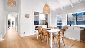Une cuisine moderne avec des meubles blancs, une table à manger et une grande fenêtre.