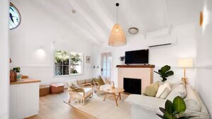 Un salon spacieux comprenant un canapé, une table basse et des fauteuils, une cheminée et un téléviseur.