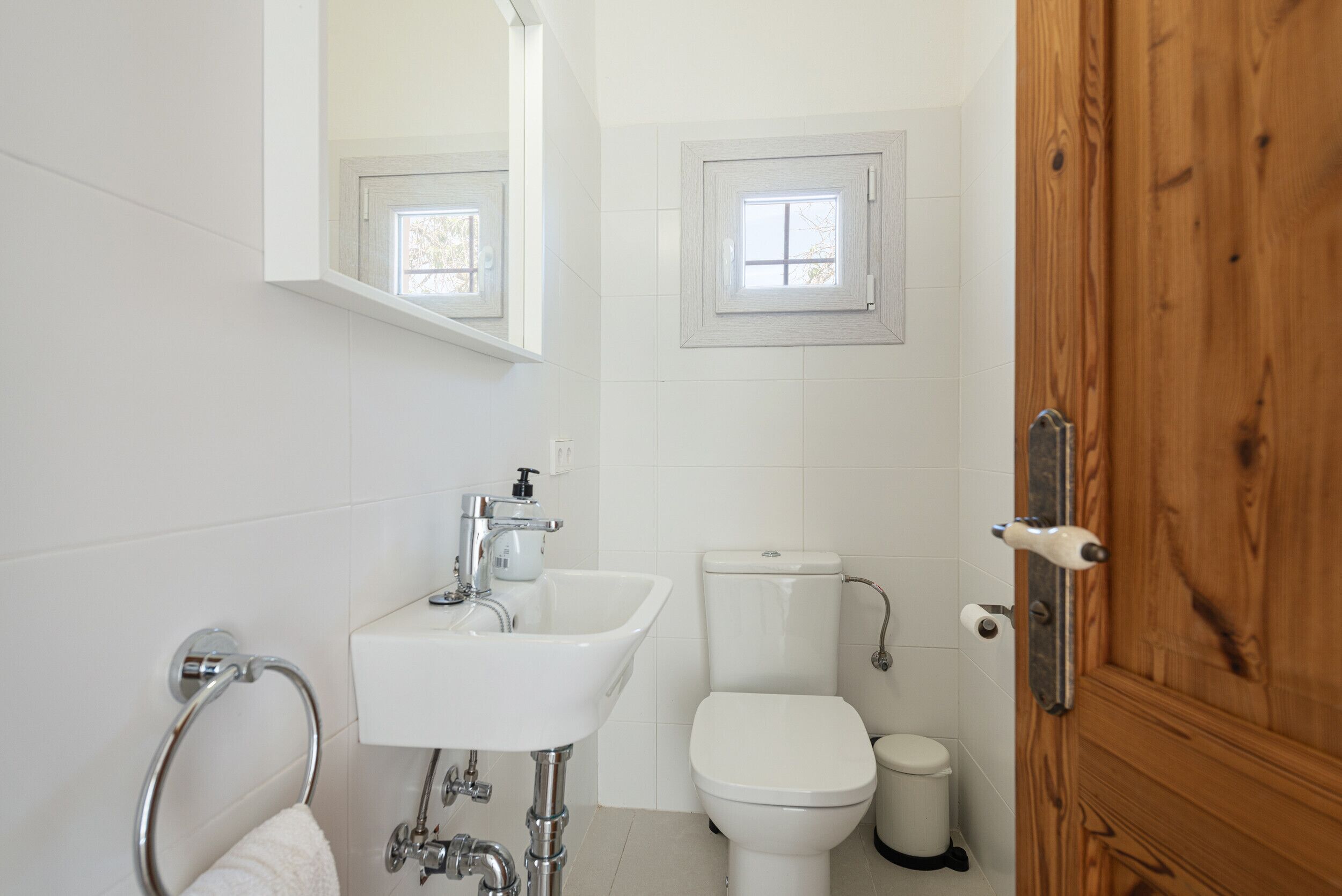Un baño con lavamanos blanco, inodoro y puerta de madera.