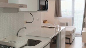 Une cuisine moderne avec des meubles blancs, un four à micro-ondes et un évier. On y trouve également un petit coin repas avec une table et des chaises.