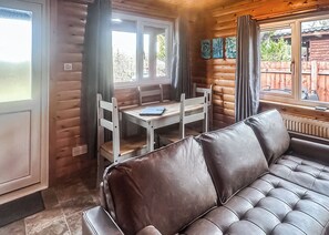 A log cabin interior with a leather sofa, wooden dining table, and chairs. - Open plan lodge with two doubles, both with TV/DVD. (Brecon Beacons National Park,)