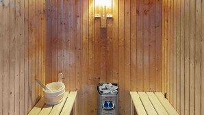 Un sauna con paredes de madera, un banco, un lavabo y un calentador con la etiqueta 'HARVIA'.