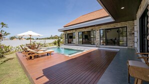 A modern house with a swimming pool, wooden deck, and outdoor furniture. - The Lotus Villa Uluwatu (Ungasan)