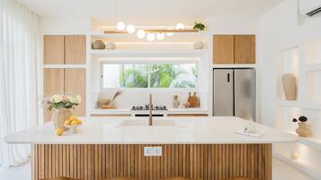 Una cocina moderna con una isla central, armarios de madera, un refrigerador de acero inoxidable y una ventana con vistas al verdor.