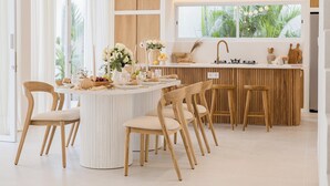 Een moderne keuken met een centraal eiland, houten stoelen en uitzicht op groen.