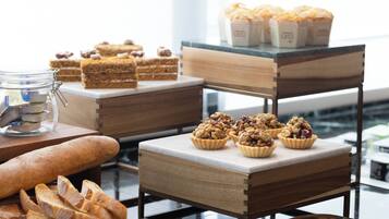 A buffet table with various baked goods, including bread, pastries, and desserts.