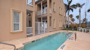 A residential building with a swimming pool, balconies, and palm trees. - Vitamin Sea | Easy Beach Living • Community Pool • 3 Min Walk to Beach (South Padre Island)