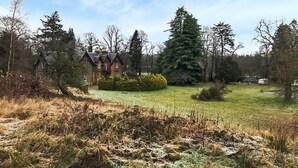 A large house with a well-maintained lawn and several trees. - Spacious, light and contemporary lodge. (Moffat)