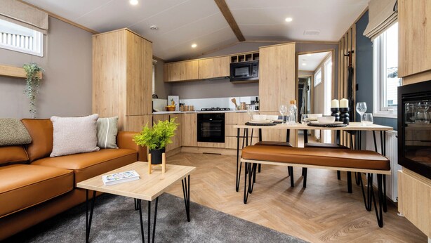 A modern kitchen with wooden cabinets, a dining area with a table and chairs, a sofa, and a small coffee table with a plant. - Spacious, light and contemporary lodge. (Moffat)