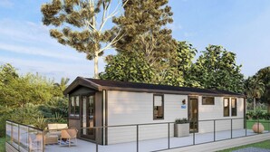 A modern, single-story building with a covered patio area, large windows, and a flat roof. - Spacious, light and contemporary lodge. (Moffat)