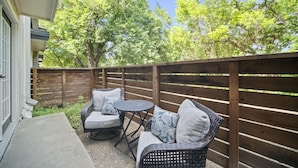 A patio with wicker furniture and a wooden fence. - Spacious and Stylish Apartment | AT&T Stadium (Arlington)