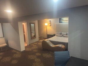 A bedroom with a bed, a chair, a desk, a mirror, and a lamp. - Hotel Dulce Maria (Tijuana)