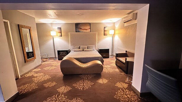 Habitació d'hotel amb un llit gran, dues taules de nit, una cadira, un escriptori i una televisió de pantalla plana.
