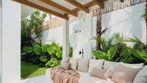 A modern outdoor seating area with a white sofa, beige cushions, and a wooden floor. - New 3BR Chic Pool Villa Near Bingin Beach Uluwatu (Bali)