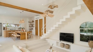 A modern living room with a staircase, a dining area, and a kitchen. - New 3BR Chic Pool Villa Near Bingin Beach Uluwatu (Bali)