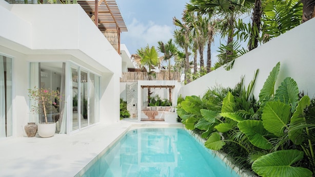 A modern pool area with white lounge chairs, a clear pool, and lush tropical plants. - New 3BR Chic Pool Villa Near Bingin Beach Uluwatu (Bali)