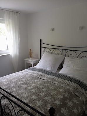 A bed with a patterned bedspread, a white pillow, and a metal headboard.
