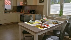 Une cuisine moderne équipée d’un four, d’un évier et d’un coin repas avec des chaises et une table dressée pour deux personnes.
