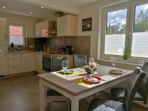 Una cocina moderna con horno, pileta y comedor con sillas y una mesa dispuesta para dos.