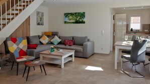 Un salon moderne avec un canapé gris, une table basse et un coin repas comprenant une table et des chaises blanches.