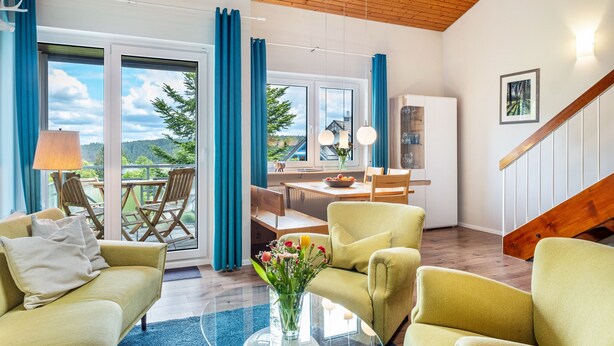 Una sala de estar moderna con sofá, sillones, una mesa de comedor y una zona de cocina.