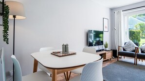 Una sala de estar moderna con una mesa de comedor, sillas, televisor y sofá.