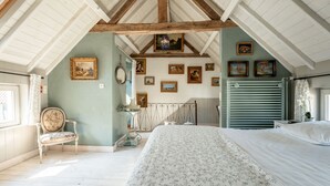 A bedroom with a large bed, a chair, a dresser, and a radiator.