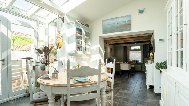 A bright dining area with a round table and white chairs, a large window, and a view of the outdoors.