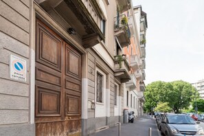 Ein Gebäude mit großen Holztüren, einem Schild für Fußgängerzone und einer schmalen Straße mit parkenden Autos und einem Baum.