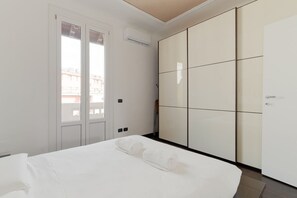 A hotel room with a bed, a wardrobe, and a door with a balcony view.