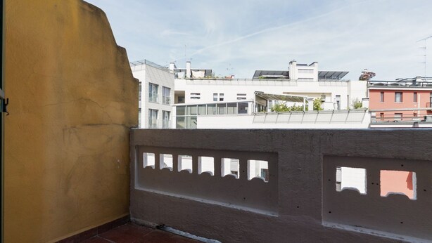 Un balcón con vistas a un edificio con varias ventanas y techo plano.