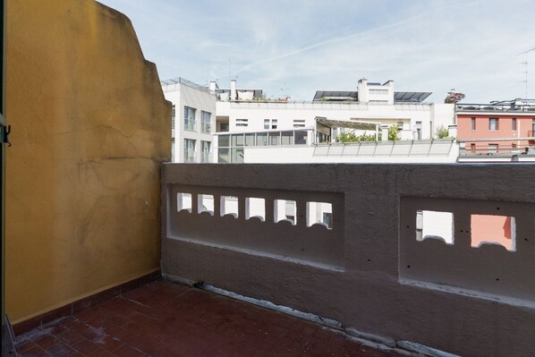 Un balcón con vistas a un edificio con varias ventanas y techo plano.