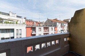 Un balcón con vista a edificios de varios pisos, incluyendo un edificio rosa y blanco con balcones.