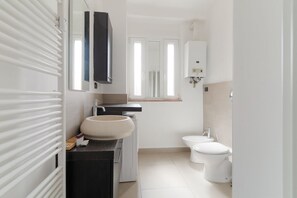 Ein modernes Badezimmer mit einem großen Waschbecken, Toilette und einem Spiegel über dem Waschbecken.
