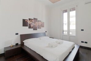Habitación de hotel moderna con una cama grande, una mesita de noche, una obra de arte colgada en la pared y una ventana con vistas.