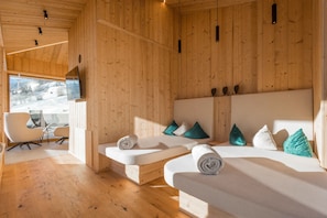 Una cabaña de madera con dos camas, un televisor y una silla.