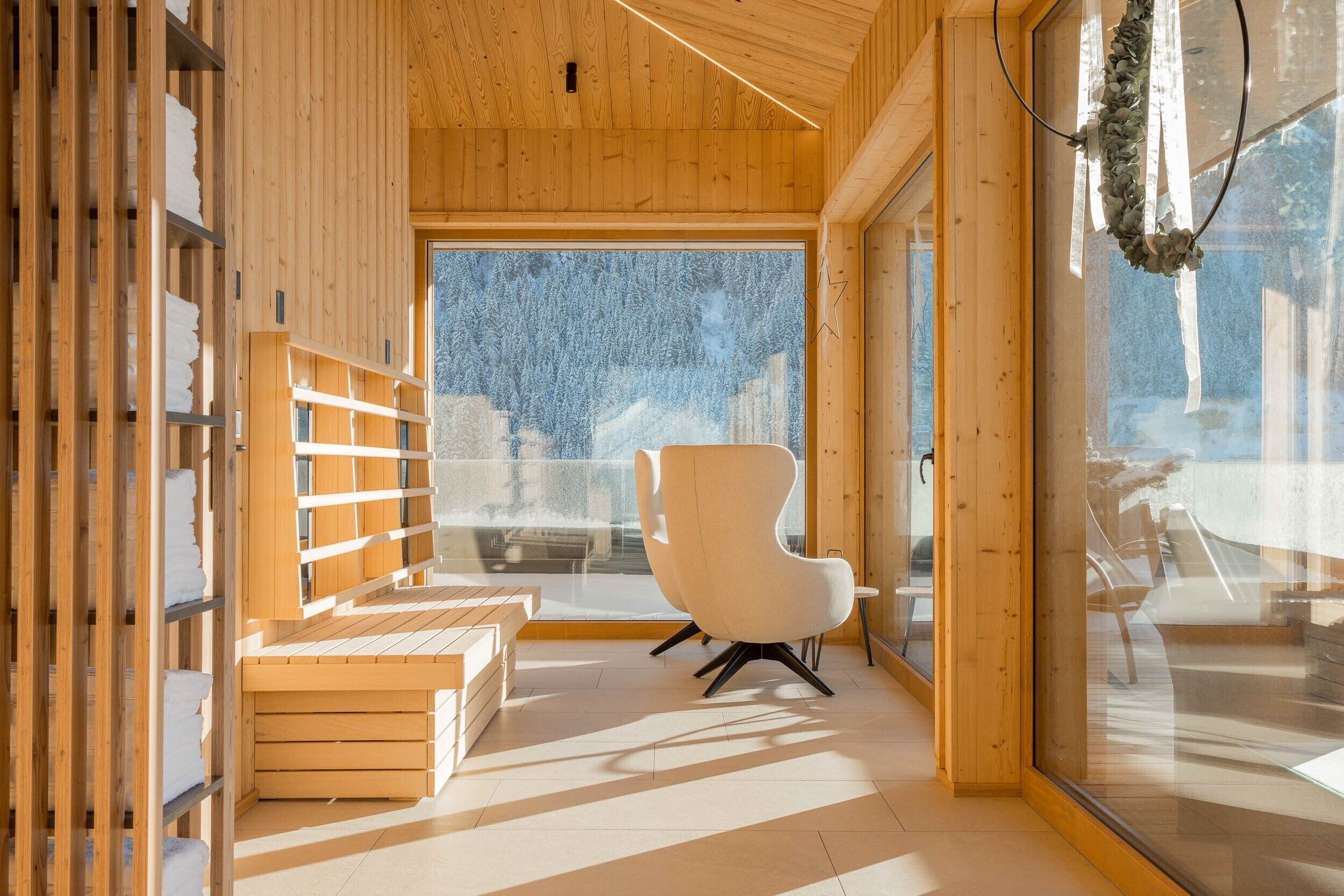 A modern interior with wooden walls, a large window, a white chair, and a wooden bench.