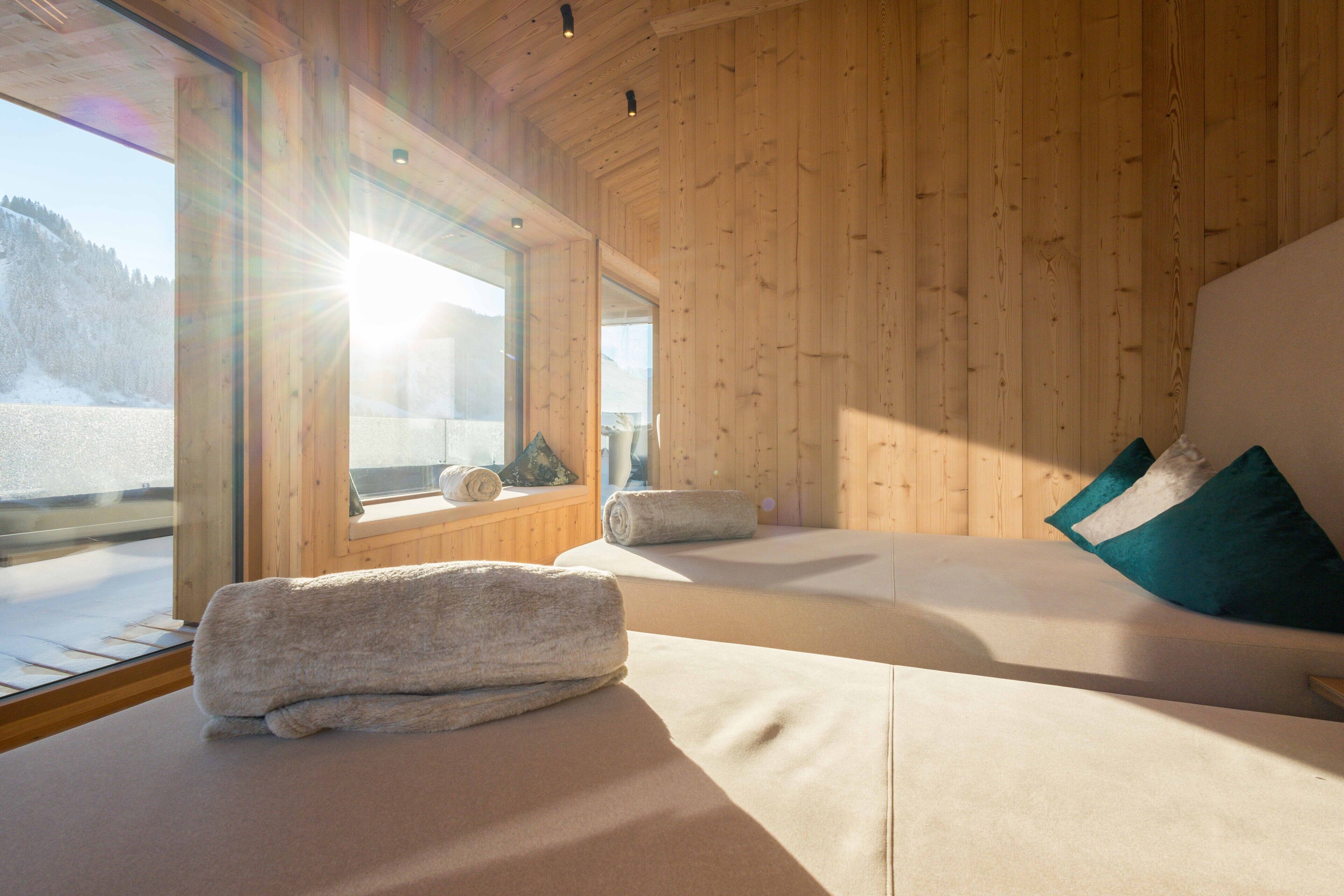 Una habitación de cabaña de madera con un ventanal grande, una cama con almohadas y una toalla sobre la cama.