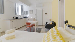 Une chambre d’hôtel compacte comprenant un lit, une petite kitchenette, un coin repas et un canapé.