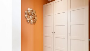 Un couloir avec un mur orange, une porte blanche dotée d’une poignée et un élément décoratif mural.