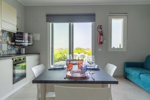 A modern kitchen with a dining area, a sofa, and a fire extinguisher.