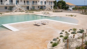 A pool area with a clear view of a building with multiple balconies and a staircase leading to the upper floors.