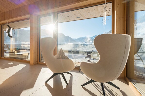 Un intérieur moderne avec deux fauteuils, de grandes fenêtres et une vue sur un paysage enneigé.