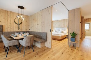 Un intérieur moderne avec un mur en bois, un coin repas avec une table et des chaises, un lit avec une tête de lit blanche et une plante en pot.