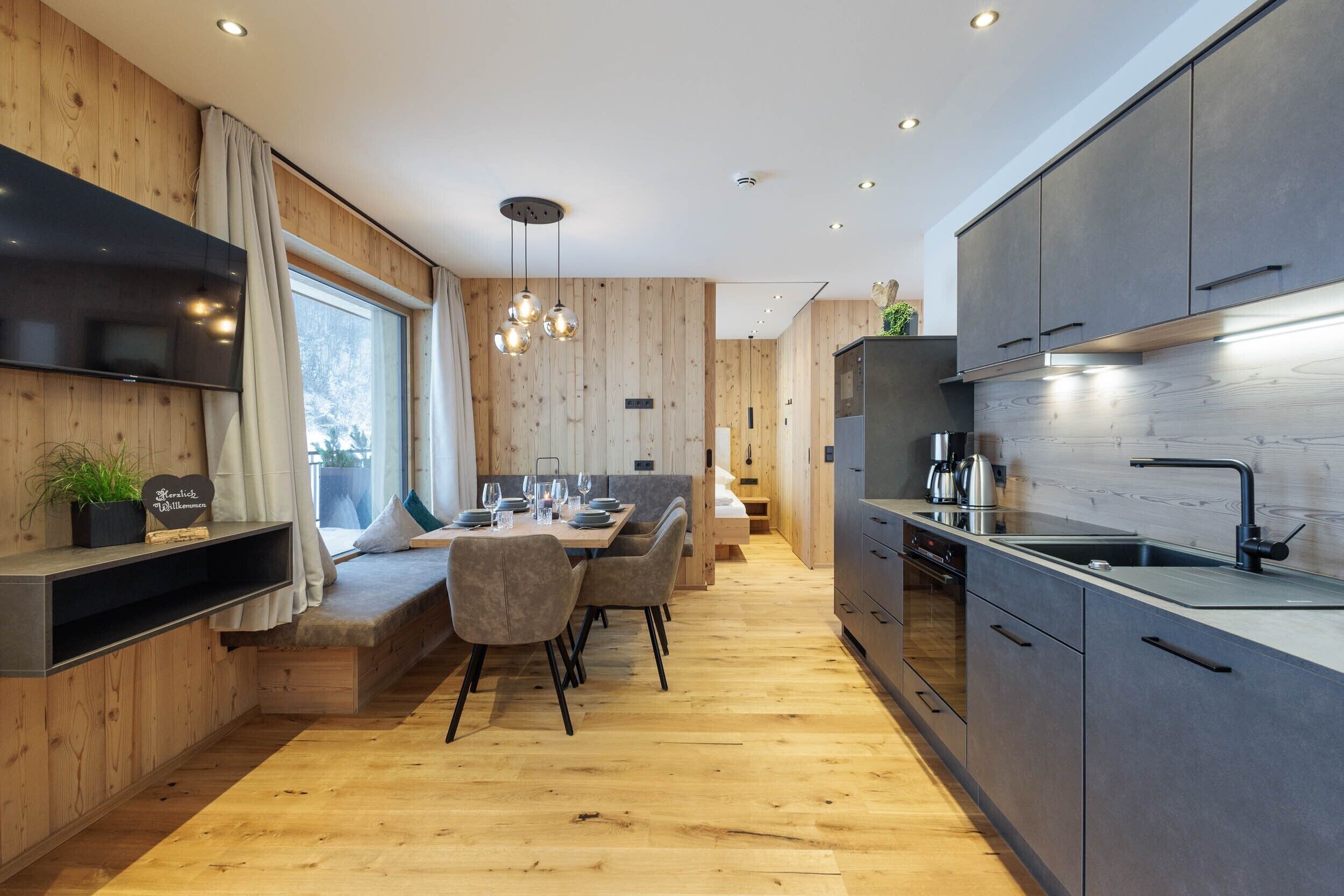 Een moderne keuken met houten wanden, een eethoek met een bank, en inbouwapparatuur.