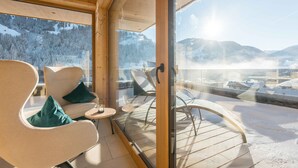 Un interior moderno con un balcón de cristal con vistas a un paisaje nevado de montaña.