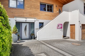 A modern building with a wooden facade, a glass door entrance, and a staircase leading to a second floor.