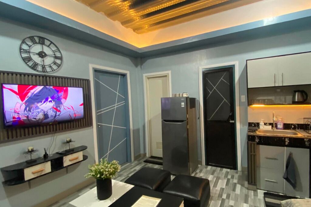 A modern kitchen with a built-in refrigerator, a dining area with a table and chairs, and a wall-mounted television.