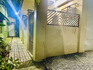 A narrow alleyway with a gated entrance, potted plants, and a tiled pathway. - 2BR at Amplayo Apartelle — Modern comfort, cozy vibes at an affordable price... (Cagayan de Oro City)